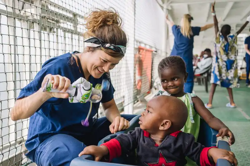 Nurse Aurélie Bourriquen with two pediatric patients outside on deck 7.