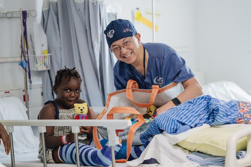 Dr. Leo Cheng, Maxillofacial Head and Neck Surgeon, handing toys out to patients in the ward.