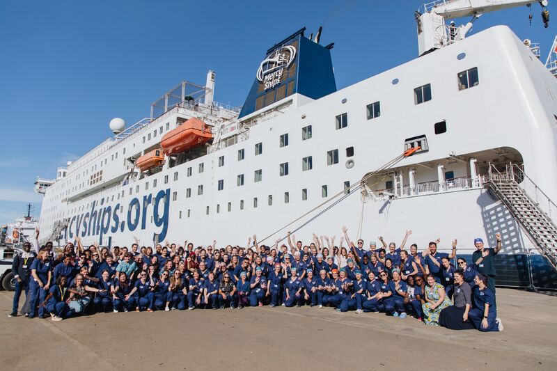 All hospital volunteers in front of the Global Mercy.